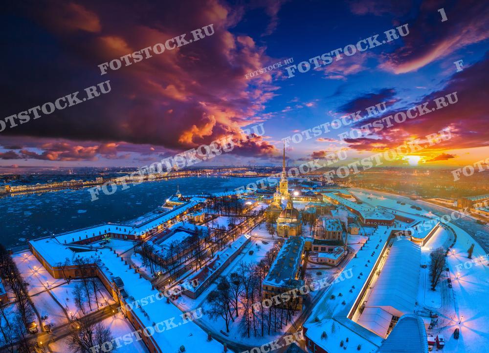 На фотографии представлен зимний вечерний вид Санкт-Петербурга с высоты птичьего полёта. В центре композиции — Петропавловская крепость.
Эта фотография может быть использована для путеводителей, туристических брошюр, исторических исследований, или как элемент дизайна в статьях и презентациях о Санкт-Петербурге и зимнем туризме в России.